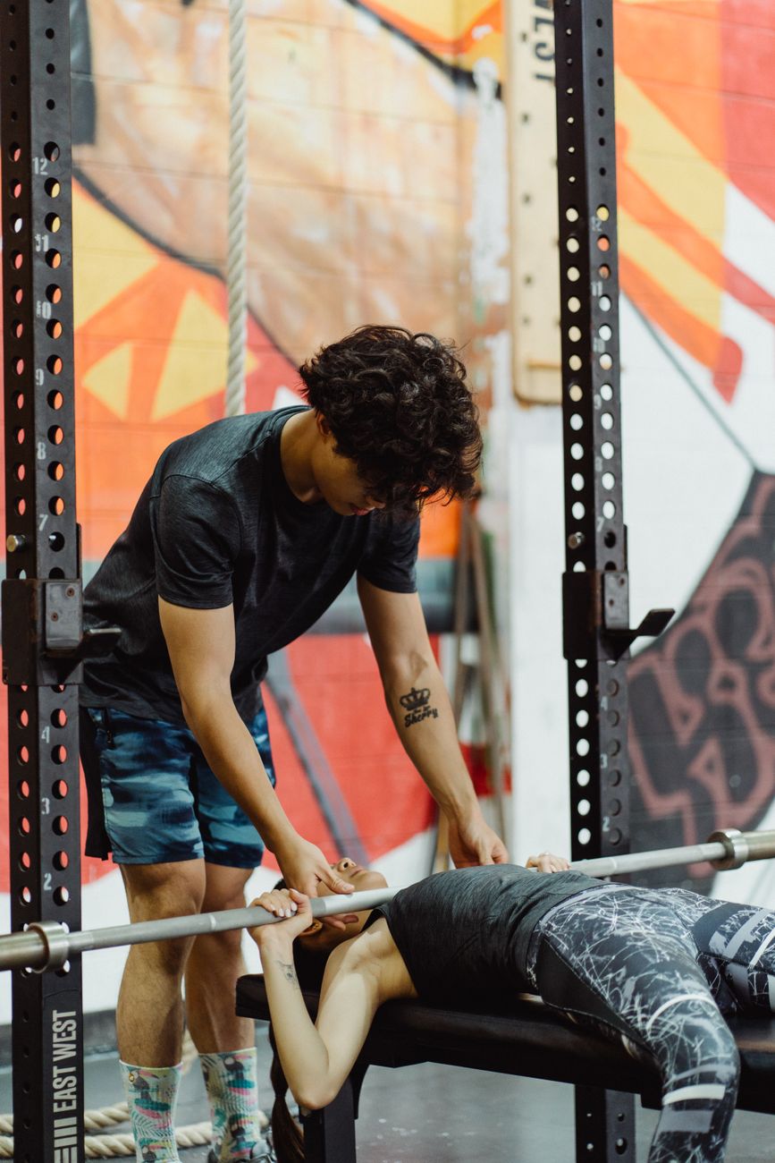 Personal trainer acompanhando aluno durante exercício